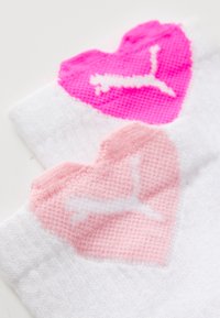 Weiße Socken mit rosa und knallpinkfarbenen Herzdesigns, die ein strukturiertes Muster aufweisen, sowie einem weißen Logo in jedem Herz. Weiches Material.