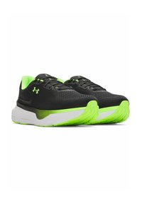 Black athletic shoes with a breathable mesh upper, green accents on the collar and sole, and a thick white midsole with textured outsole.