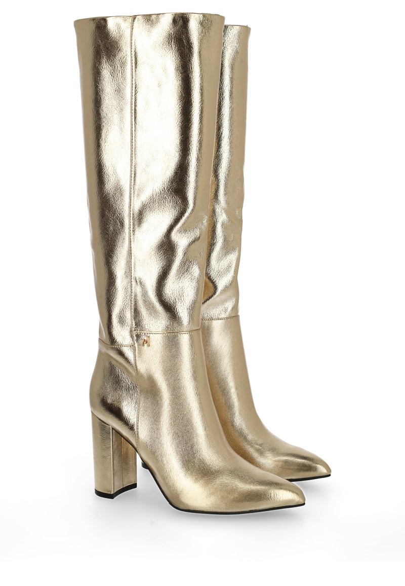Błyszczące metaliczne złote buty za kolano z ostrymi noskami i masywnymi wysokimi obcasami, wyeksponowane obok siebie na białym tle.