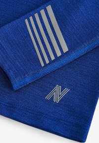 Blauw sporttextiel met een gladde textuur, voorzien van een gestreept grijs grafisch ontwerp en een grijs logo in de onderste hoek.
