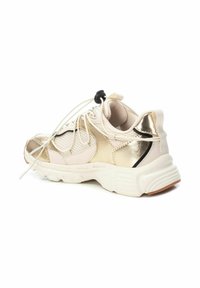 Zapatilla deportiva con un upper metálico en blanco y dorado, paneles de malla, cordones elásticos y una suela de goma. Cuenta con una puntera redondeada y acentos texturizados.