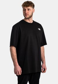 T-shirt nera a maniche corte in cotone, con scollatura a girocollo e un piccolo logo bianco sul lato sinistro del petto. Vestibilità semplice e rilassata.