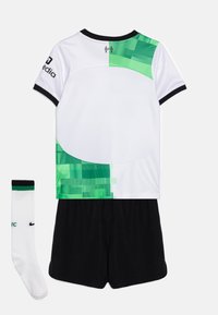 Camiseta deportiva blanca y verde de manga corta, con ribetes negros, pantalones cortos negros a juego y un calcetín blanco con detalles en negro y verde.
