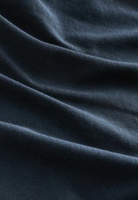 Donkerblauwe textuurstof met zichtbare plooien, gemaakt van geweven materiaal, met een subtiel, gestructureerd patroon.