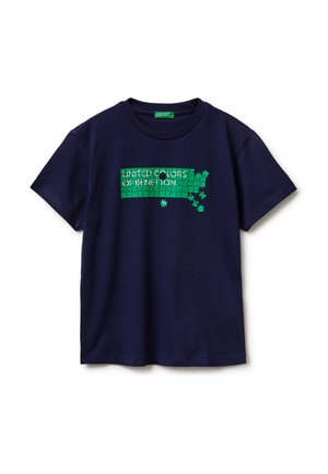 Maglietta blu navy con una grafica di puzzle verde e il testo "United Colors of Benetton", con alcuni pezzi di puzzle mancanti e staccati.