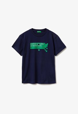 Camiseta azul marino con un gráfico de un rompecabezas verde y el texto "United Colors of Benetton", con algunas piezas del rompecabezas faltantes y desprendidas.