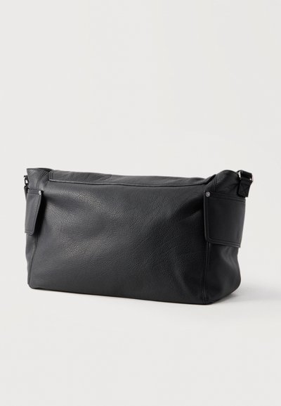 Sac de sport rectangulaire en cuir noir texturé avec rabats de poche latéraux et bandoulière ajustable sur fond clair uni.