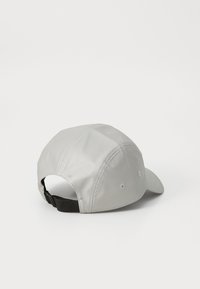 Lichtgrijze pet met een gebogen klep, gemaakt van glad materiaal. Voorzien van ventilatiegaten en een verstelbare zwarte strap aan de achterkant.