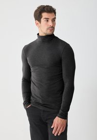 Cămașă neagră cu guler înalt, realizată dintr-un material neted și elastic, design ajustat, mâneci lungi, cu un guler rulat și cusături minimale.