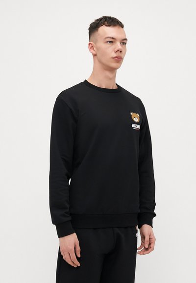 Black sweatshirt made of cotton blend, featuring a round neck, long sleeves, and a bear graphic logo on the left chest. Ribbed cuffs and hem.