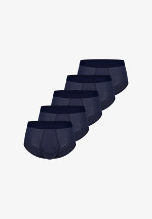 Caleçons rayés bleu marine pour hommes avec une ceinture unie. Le matériau semble lisse ; la coupe ajustée met en valeur la silhouette. Modèle debout pieds nus, bras croisés.