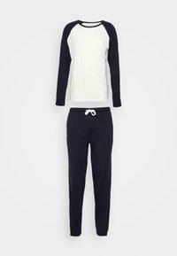 Langsleeve witte en marineblauwe raglan top, gecombineerd met marineblauwe elastische tailleband broek met een trekkoord. Zachte katoenmix stof, casual pasvorm.