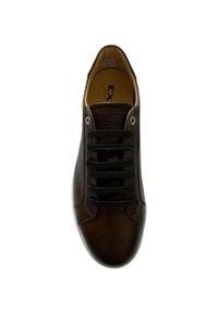 Sneaker in pelle marrone con lacci neri, punta arrotondata e design minimalista. Presenta una superficie liscia e una sottile personalizzazione sulla linguetta.