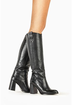 Czarne skórzane kozaki do kolan z kwadratowym noskiem, teksturowanym wykończeniem i masywnym obcasem na słupku. Posiadają wysoką cholewkę i subtelne przeszycia.