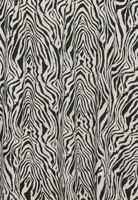Motif de rayures zébrées noir et blanc à orientation verticale sur un fond en tissu texturé.