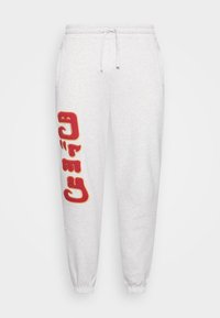 Grå sweatpants med elastisk midjeband, dragsko och ribbade muddar. Har en stor röd grafiktryck på vänster ben. Mjuk textur.