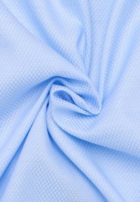 Tessuto di colore azzurro chiaro con motivo a diamante, dalla consistenza morbida e leggermente lucida, drappeggiato per mostrare pieghe e fluidità.