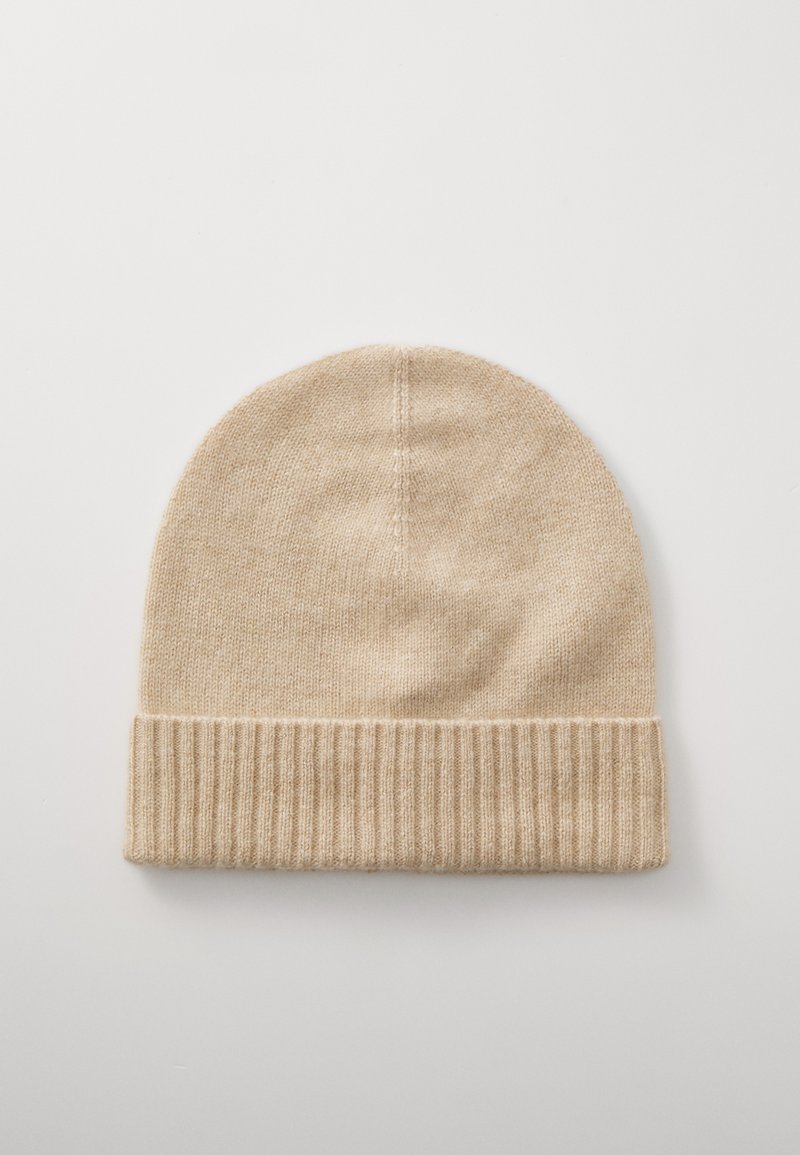 Brede beige beanie met een geribde manchet. Zachte textuur en ronde vorm, met een gladde afwerking en subtiele naden.