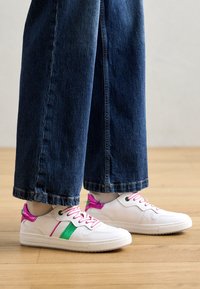 Vita sneakers med rosa och gröna detaljer, med en slät yta, snörning och perforerade detaljer på sidorna.