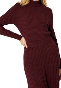 Bordowy sweter z golfem o prążkowanej strukturze, z długimi rękawami, z dopasowaną talią i miękką teksturą. Prosty design bez wzorów i ozdób.