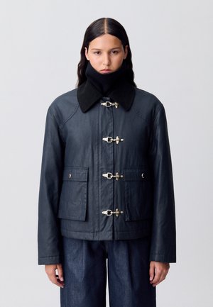 Veste imperméable bleu marine, avec un col noir, des fermetures à cordon, et deux poches avant. Fabriquée dans un matériau lisse et durable.