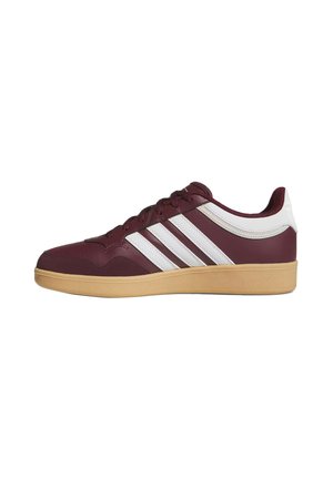 Niski bordowy sneaker z białymi paskami i obszyciem, jasnobrązową gumową podeszwą i sznurowaniem z przodu, widziany z boku na białym tle.