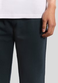 Svarta träningsoveraller med en slät yta, sidofickor och en åtsittande design, tillsammans med en vit, strukturerad kortärmad topp.