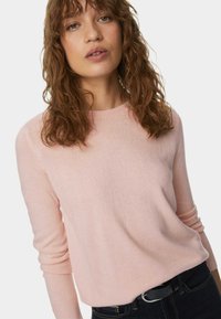 Maglione a maglia rosa chiaro con maniche lunghe e scollatura a girocollo. Texture morbida, vestibilità rilassata, abbinato a jeans di denim scuri e una cintura nera.