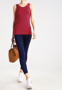 Punainen ja laivaston sininen raidallinen hihaton paita, tiukka malli, yhdistettynä laivaston sinisiin legginsseihin ja valkoisiin tennareihin. Ruskea käsilaukku viimeistelee asun.