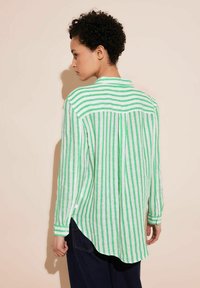 Green and white striped long-sleeve shirt made of lightweight fabric, featuring a button closure, curved hem, and a back yoke detail.