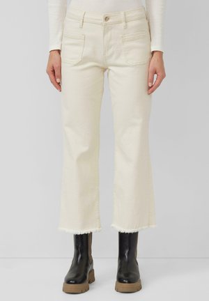 Crème-kleurige wijdvallende jeans met rafelige zomen, vijf-pocket ontwerp en een knoopsluiting, gecombineerd met zwarte chunky laarzen.