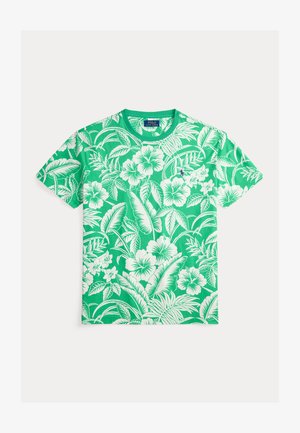 Grønn bomulls-t-skjorte med hvitt hibiskusblomstermønster. Rund hals og korte ermer. Myk tekstur med livfulle farger.