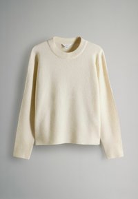 Maglione color crema realizzato in morbido tessuto, con scollatura rotonda classica e polsini e orlo a coste; maniche lunghe, vestibilità morbida.