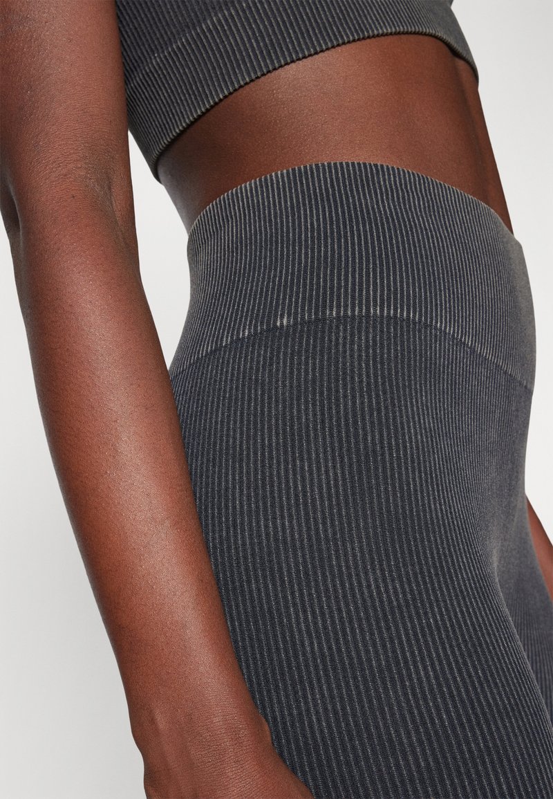 Dunkel gerippter Sport-BH und Leggings mit einem breiten Bund. Der Stoff wirkt weich und dehnbar und hat vertikale Streifen.