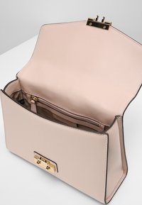 Strukturerad handväska i ljusrosa läder med guldfärgad hårdvara, med låsning och en zip-försedd innerficka. Slät textur, minimalistisk design.