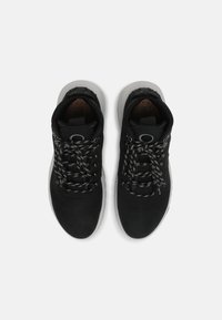 Sapatilhas desportivas pretas com um cabedal liso, sola branca em contraste e atacadores texturizados em preto e branco. Apresentam um colarinho acolchoado para maior conforto.