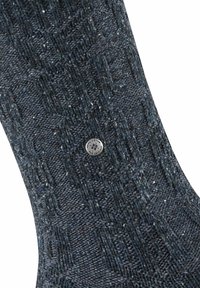 Ciemnoniebieska dziana skarpetka z teksturowanym wzorem i małym srebrnym logo. Tkanina ma subtelne jasne plamki rozproszone w całej powierzchni.