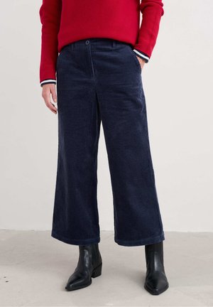 Navy corduroy wide-leg pants with a button closure, front pockets, and a ribbed texture, paired with black heeled ankle boots.