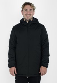 Sort isoleret jakke med hætte, frontlynlås og elastiske manchetter. Har et logo-patch på venstre arm; glat, tekstureret materiale.