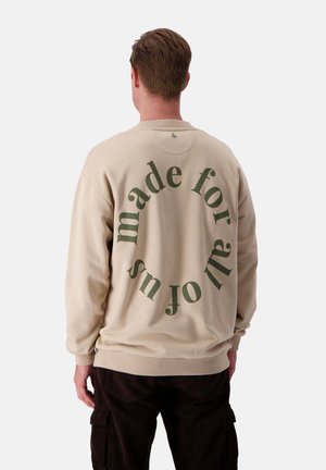 Beiger Sweatshirt mit grünem, kreisförmigem Text "gemacht für uns alle" auf der Rückseite. Mit gerippten Bündchen und Saum, aus weichem Stoff gefertigt.