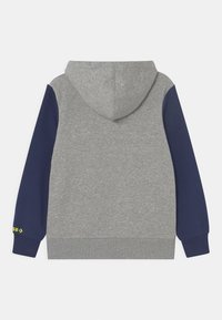 Felpa con cappuccio dal corpo grigio e maniche blu navy, realizzata in un tessuto morbido. Presenta polsini a coste e un logo in giallo brillante.