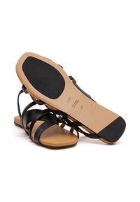 Schwarze Leder-Sandalen mit einem Riemchen-Design, beigefarbenem Fußbett und einer flachen Gummisohle mit strukturiertem Boden für besseren Halt. Größe 37.