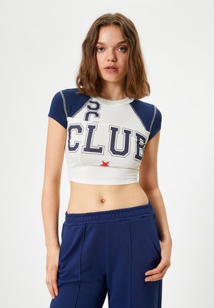 Top atlético recortado con mangas cortas en marino, cuerpo blanco, gran gráfico de "CLUB" y acento de estrella roja. Tejido suave y elástico, adecuado para ropa deportiva.