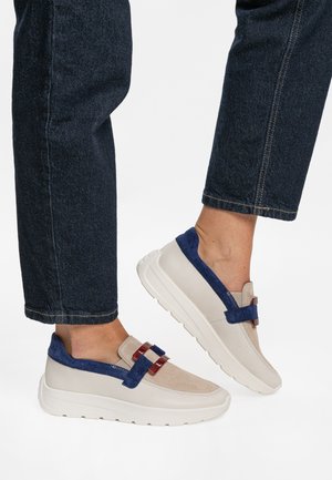 Beige and navy shoes with a smooth leather finish, featuring a textured suede accent and a decorative buckle. Thick white sole.