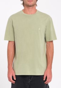 Camiseta de manga corta en algodón verde claro con cuello redondo y un pequeño detalle de logotipo en un tono contrastante en el pecho.