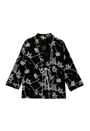 Veste style kimono noire avec imprimé floral blanc, passepoil blanc le long des bords et fermeture à nouer à l'avant.