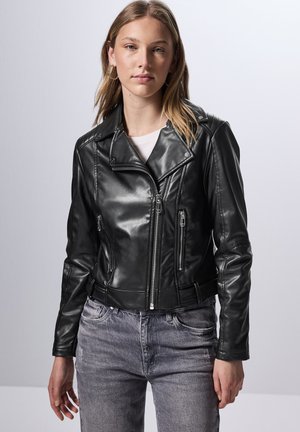 Veste de motard en cuir noir avec un design court, poches zippées et col cranté. Présente une texture brillante et un haut blanc en dessous.