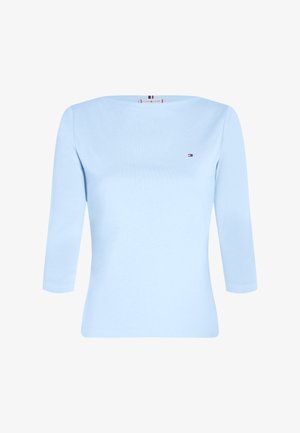 Light blue long-sleeve top in soft cotton, featuring a round neckline and small logo embellishment on the chest. Smooth texture, fitted design.