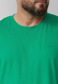 Zielona bawełniana koszulka z okrągłym dekoltem. Posiada subtelne wytłoczone logo marki s.Oliver na froncie. Gładka tekstura i prosty design.