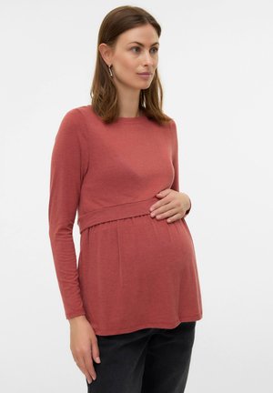 Graviditetsbluse i støvet rosa, lange ærmer, blød bomuldsblanding, empiretalje med samling, parret med mørke bukser.